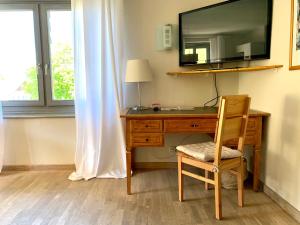 escritorio con silla y TV en la parte superior en Sonnenhof - Ferienwohnung, en Oberstaufen