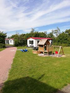 un cortile con parco giochi e una casa di Minicamping Wisse a Meliskerke