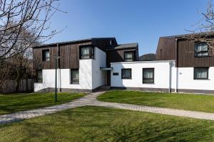 Una gran casa blanca con un patio de césped. en Maurers Schlierseetraum 1 hochwertige Erdgeschosswohnung mit allen Raffinessen erfreut sich auch Urlauber idealerweise für Paar mit Kindern geeignet und Vierbeiner Dank des tollen Zauns auf der Terrasse stylisch und edel von der Ausstattung mit 64 qm, en Schliersee