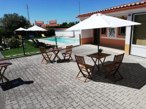 a patio with a table and chairs and an umbrella at Quinta Sao Martinho in Reguengo Grande