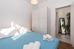1 dormitorio con 1 cama azul y 2 toallas en Apartments Bruna Trogir en Trogir