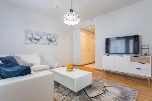 a living room with a white couch and a tv at Tuomas´ luxurious suites, Kelo in Rovaniemi