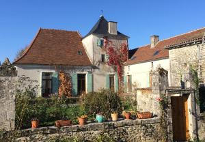 uma antiga casa branca com uma parede de pedra e edifícios em Nature et Piscine au sommet du Périgord em Tourtoirac