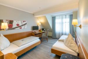 um quarto de hotel com duas camas e uma secretária em Landhotel Zur Bretzel em Babenhausen