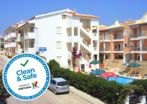 a sign in front of a building with a pool at Apartamentos Cabrita in Albufeira