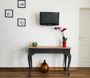 a table with a tv on a wall with flowers on it at LE COSY LOIRE appart in Les Rosiers-sur-Loire