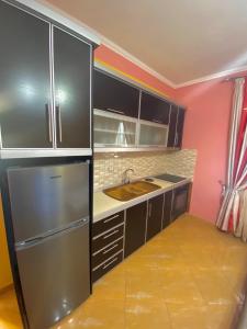 Duraj Apartment في سارنده: مطبخ مع دواليب سوداء وثلاجة حديد قابلة للصدأ
