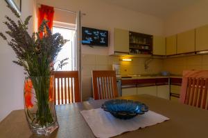 a kitchen with a table with a vase of flowers on it at Apartman Haus Maja in Banjol