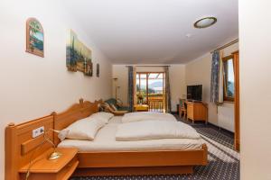 a bedroom with two beds and a desk and a television at Hotel Fasching in Sankt Georgen am Längsee