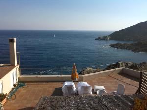 a patio with chairs and an umbrella and the ocean at Barca Serena in Port de la Selva