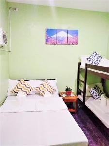 a bedroom with two white beds and a table at FilCan Hostel/Backpackers in Coron