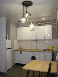 a kitchen with white cabinets and a wooden table at Квартира студия в центре Чернигова wi-fi in Chernihiv