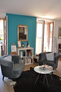 a living room with two chairs and a blue wall at Chez Cathy chambre chez l'habitante in Bremis