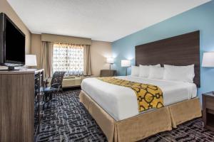 a hotel room with a large bed and a flat screen tv at Baymont by Wyndham Joliet in Joliet