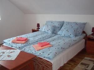 uma cama com lençóis azuis e toalhas cor-de-rosa em Szikla Vendégház em Istenmezeje