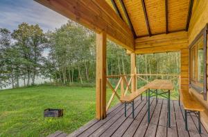 um alpendre de madeira com uma mesa e uma cadeira. em Sauna with the Private Lake Access em Molėtai