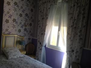 a bedroom with a bed and a window with curtains at A l'ombre du cedre in Hyères