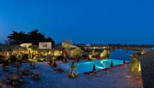 un complexe doté d'une piscine avec des chaises et des lumières dans l'établissement Hôtel L' Estelle en Camargue, à Saintes-Maries-de-la-Mer