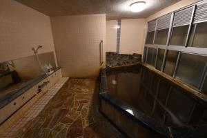 La salle de bains est pourvue d'une grande baignoire avec de l'eau. dans l'établissement Onsen Inn Hamayu Nagi / Vacation STAY 81903, à Beppu