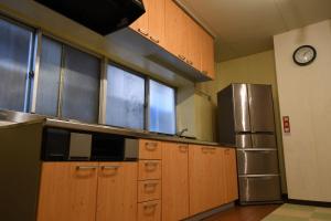 La cuisine est équipée d'armoires en bois et d'un réfrigérateur en acier inoxydable. dans l'établissement Onsen Inn Hamayu Nagi / Vacation STAY 81903, à Beppu