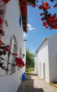 Un bâtiment blanc avec des fleurs rouges sur son côté dans l'établissement Quinta dos Cochichos - Country Houses, à Olhão