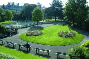 un homme assis sur un banc dans un parc dans l'établissement Appart Hotel Montchapet Dijon Centre, à Dijon