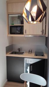 une cuisine avec un évier et une lumière sur un comptoir dans l'établissement Appart Hotel Montchapet Dijon Centre, à Dijon