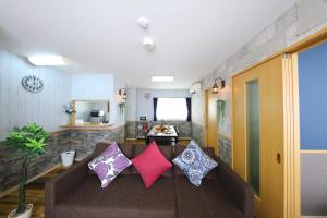 a living room with a brown couch with colorful pillows at Prosper 6th Building 2F / Vacation STAY 7562 in Nagoya