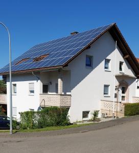 una casa blanca con paneles solares en el techo en Ferienwohnung Kempf Mandelbachtal, en Ommersheim