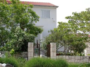 a white house behind a fence with trees at Apartments Curin in Hvar