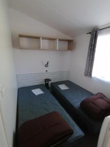 Cette petite chambre comprend 2 lits et une fenêtre. dans l'établissement Camping de masevaux, à Masevaux