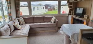 a living room with a couch and a tv at KSR Hot Tub Holiday Home at Tattershall Lakes in Tattershall