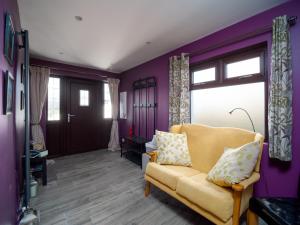 a living room with a yellow couch and purple walls at A fourteen in Kilkeel
