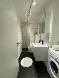 a white bathroom with a sink and a washing machine at Bella Luna in Überlingen