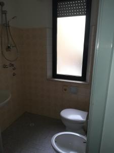 a bathroom with a toilet and a sink and a window at Hotel Pigalle in Rimini