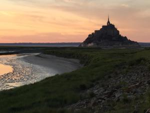 a castle on an island in the ocean at sunset at Au Bon Accueil in Saint-Marcan