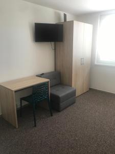 een kamer met een bureau, een stoel, een tafel en een televisie bij Apartmánové ubytovanie in Vranov nad Topľou