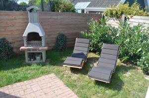 three lounge chairs and a pizza oven in a backyard at Ferienhauser Lensterstrand in Lenste