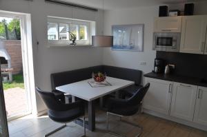 a kitchen with a white table and black chairs at Ferienhauser Lensterstrand in Lenste