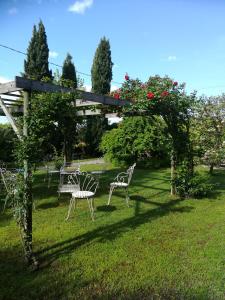 two chairs and a table in a yard with an arch with roses at Casa Pianta in Cavallino-Treporti