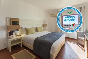 
a hotel room with a bed and a clock on the wall at Best Western Hotel Dom Bernardo in Faro
