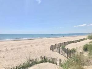 een hek op een strand met de oceaan op de achtergrond bij Studio le couchant in La Grande-Motte