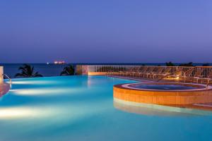 a swimming pool with chairs and the ocean at night at Hotel Irotama XXI in Santa Marta