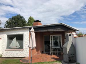 ein kleines Haus mit einem Tisch und einem Sonnenschirm in der Unterkunft Ferienhauser Lensterstrand in Lenste