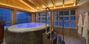 a bathroom with a large tub in a room with windows at Hotel pod Lipou RESORT in Modra +53 photos