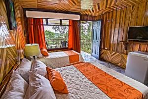 a bedroom with two beds and a flat screen tv at Mar Inn Costa Rica in Monteverde Costa Rica