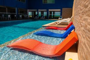 a swimming pool with two lifeguard chairs and a swimming pool at Pousada Laguna Hotel in Cabo Frio