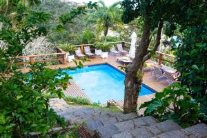 a swimming pool with chairs and a wooden deck at Eco Vila Beija Flor in Búzios