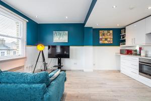 a living room with blue walls and a blue couch at Cozy and Charming Flat: Minutes from Everything! in London