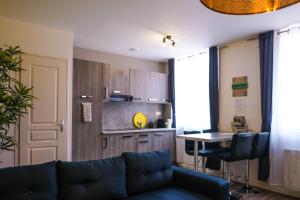 ein Wohnzimmer mit einem Sofa und einem Tisch sowie eine Küche in der Unterkunft Le Business House in Saint-Omer